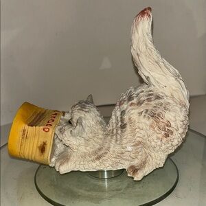 figurine depicting a cat with its head stuck inside a food can.